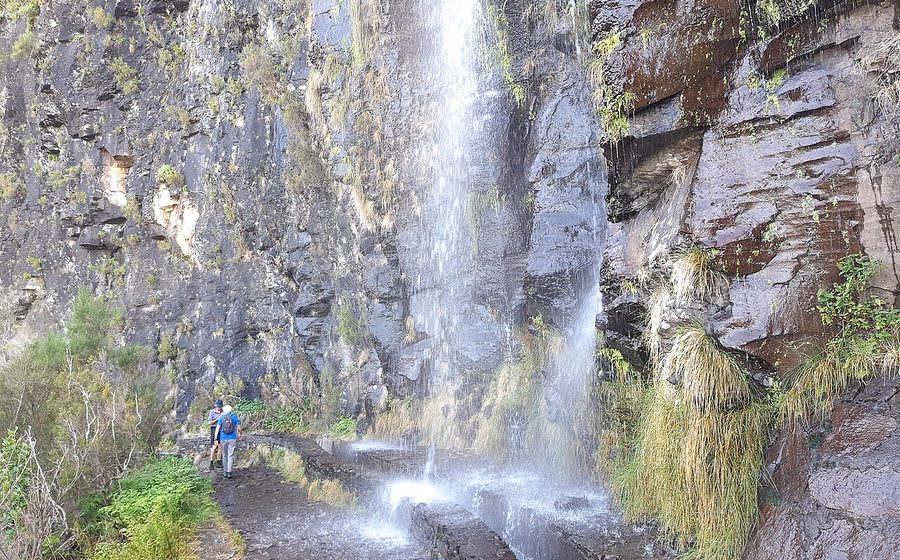 A waterfall pouring over the levada path near Encumeada